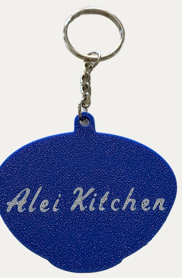 The reverse of the keychain in deep blue, carrying the name Alei Kitchen.